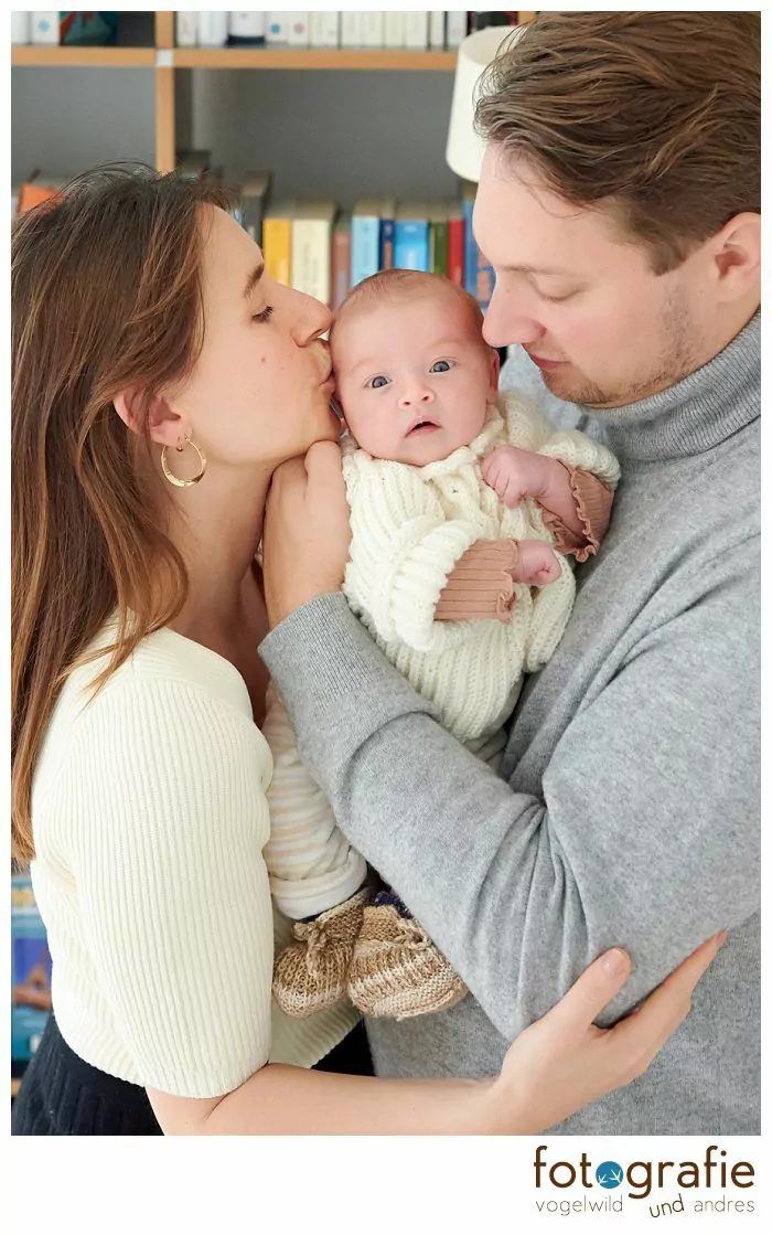 Familie mit Baby vor Bücherwand